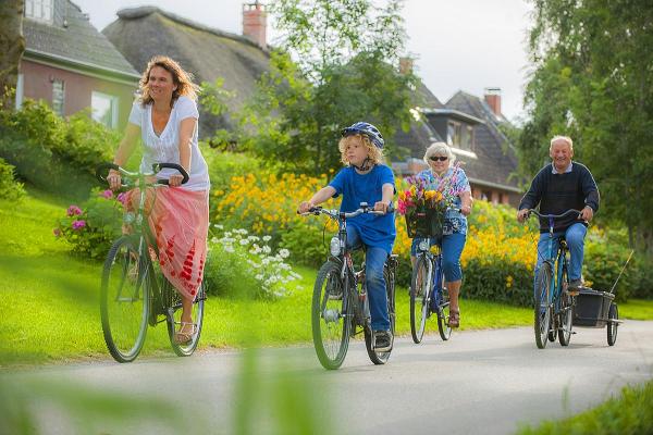 Familie auf Rädern vor Reetdachhäusern