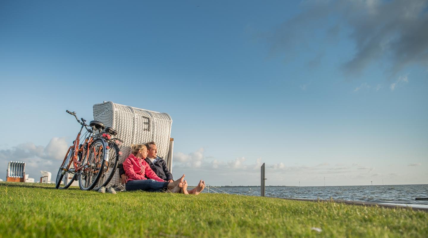 Paar mit Fahrrädern am Dockkoog an einen Strandkorb gelehnt